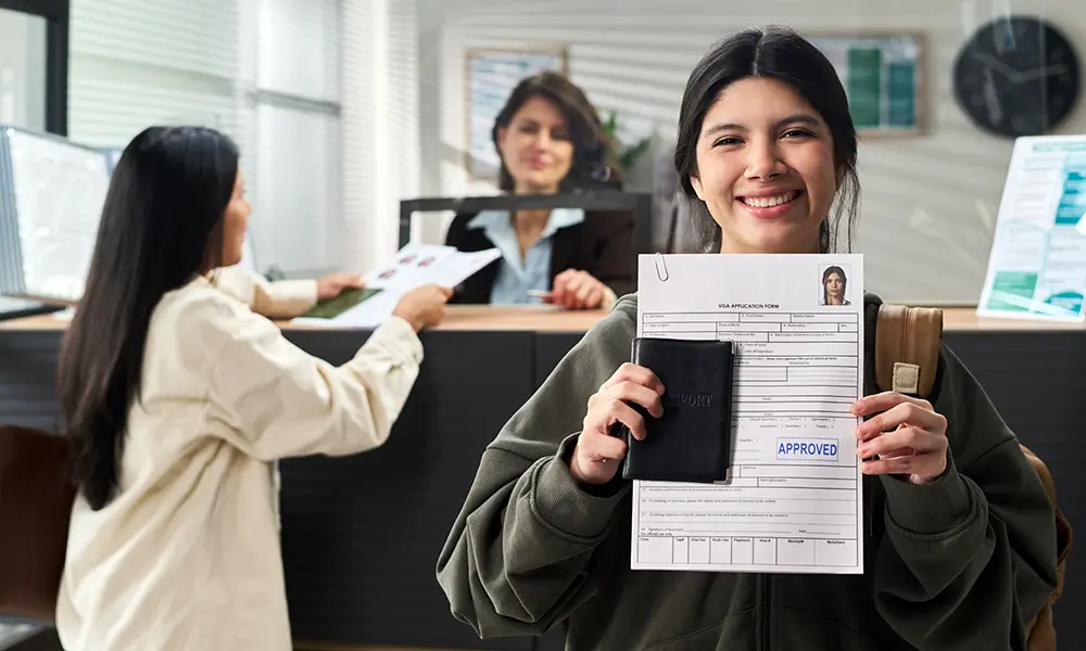 Smiling traveler holding an approved visa application form and passport at a processing center.
