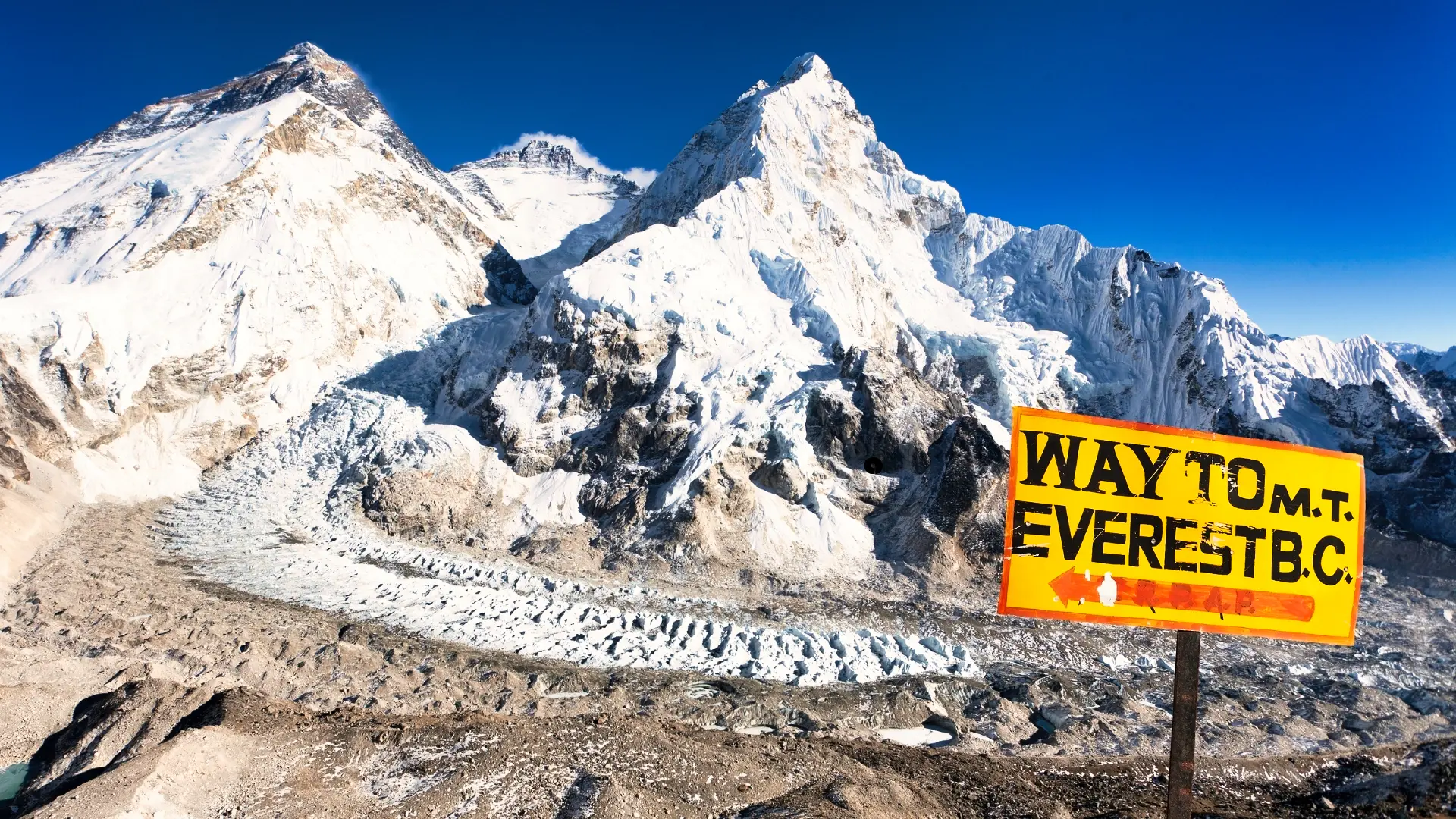 Yellow sign marking the way to Mt. Everest B.C. in Nepal, overlooking Khumbu Glacier and Mount Everest.