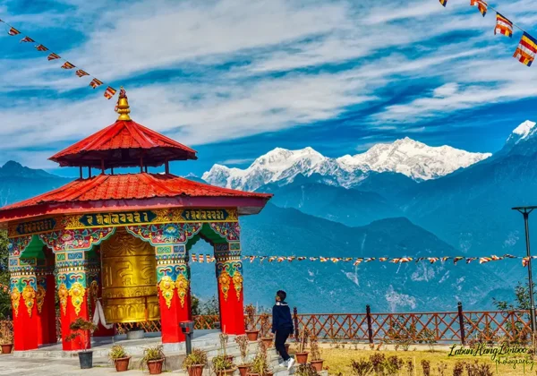 Epic view of a vibrant golden prayer wheel in Sikkim, framed by flying flags and the towering Mt. Kanchenjunga.