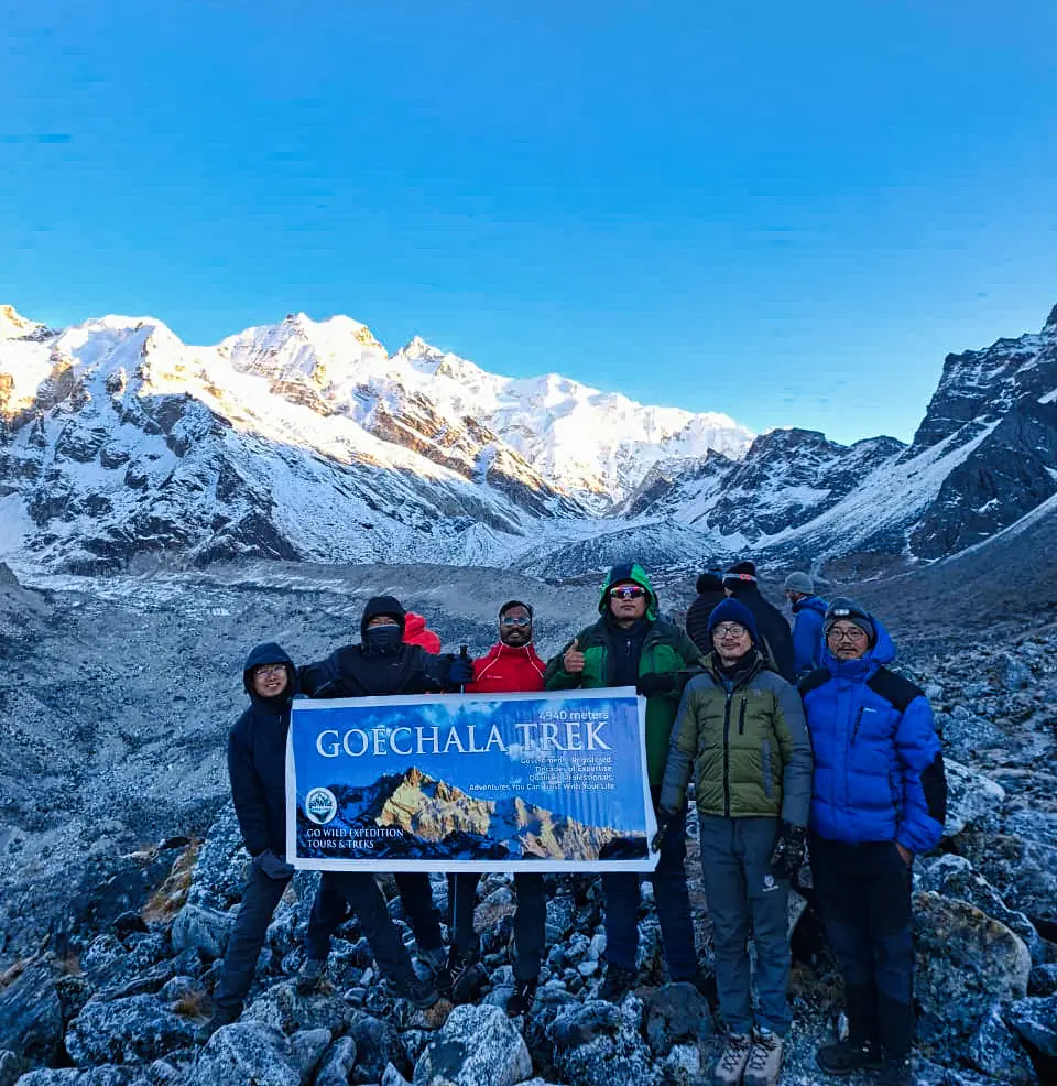 Sikkim travel agent Go Wild Expedition guiding a group at Goechala Viewpoint 1, backed by Mt. Kanchenjunga's moraines